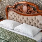 В номере двуспальная кровать с прикроватными тумбами и бра.