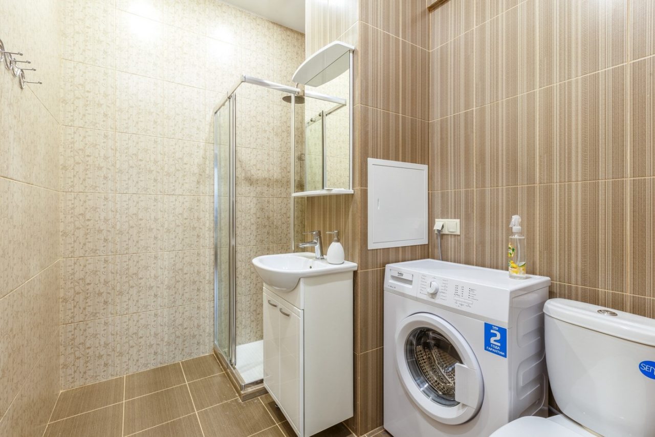 Светлая ванная комната с душем и стиральной машинкой