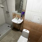 Светлая ванная комната с душевой кабиной, раковиной и ТЦ.