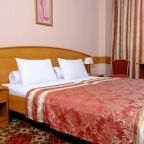 Вид на уютную спальню с ковролином и тумбой у кровати.