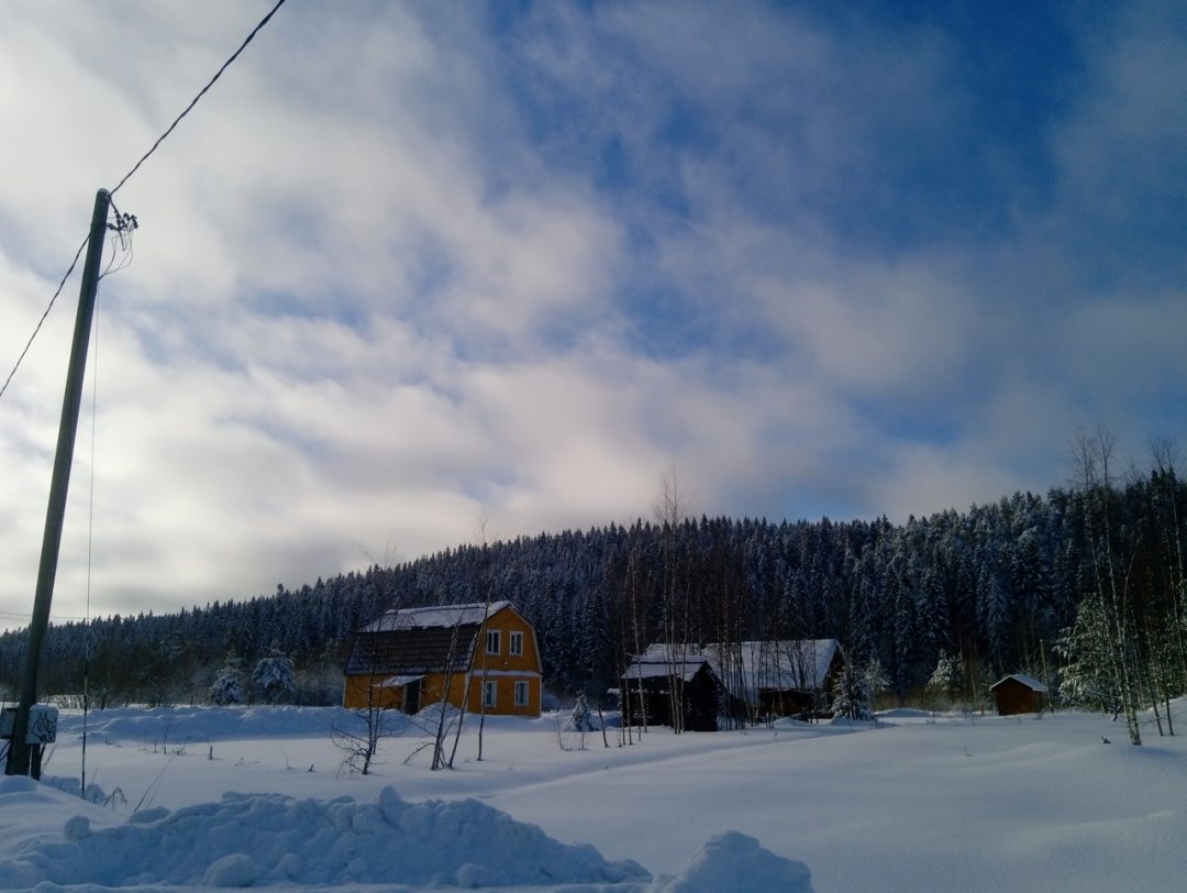 Вид на дом зимой со стороны проселочной дороги. Уютный дом в Карелии в окружении леса