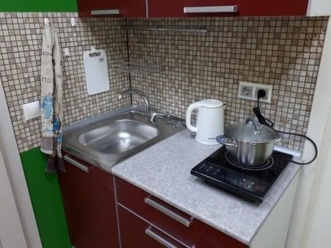 кухня с индукционной плиткой, раковиной и электрочайником.