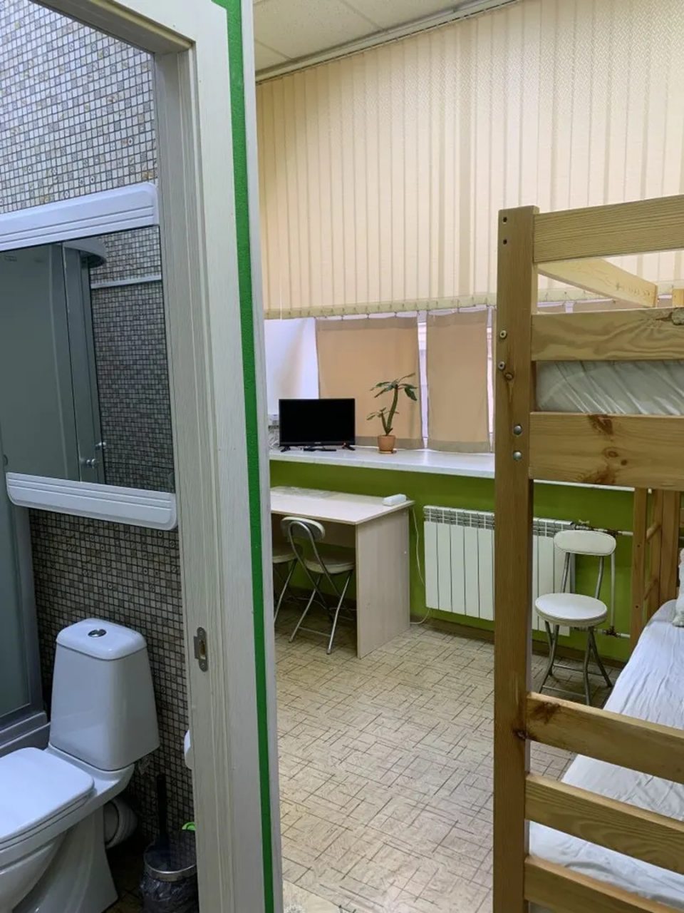 общая панорама номера: туалет, кровать, большое окно, ТВ