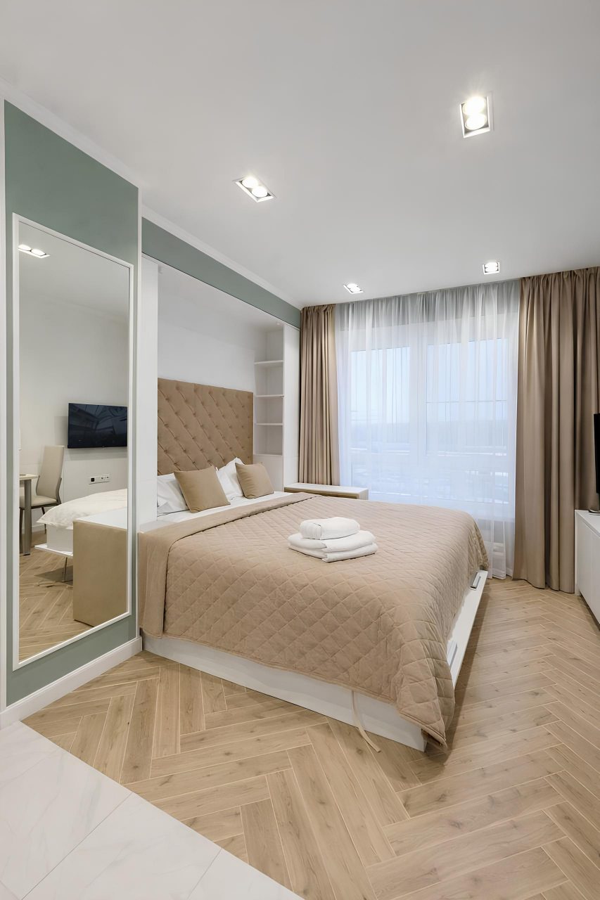 Современная спальня в бежевых тонах и с панорамным окном.