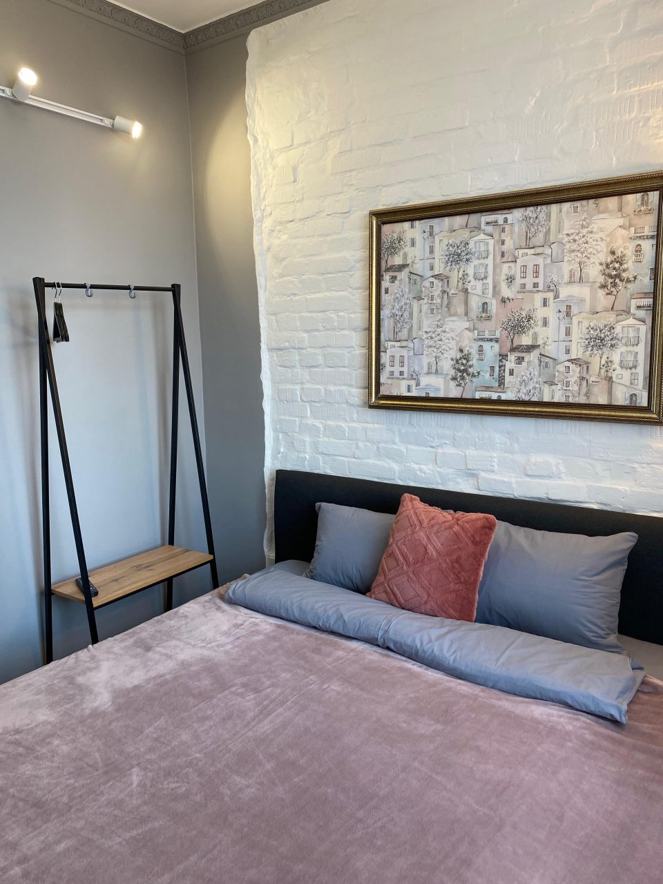 Спальня с кроватью, телевизором и вешалом для одежды