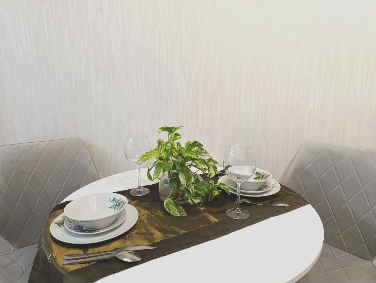 На кухне круглый стол, посуда для сервировки, приборы.