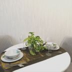 На кухне круглый стол, посуда для сервировки, приборы.