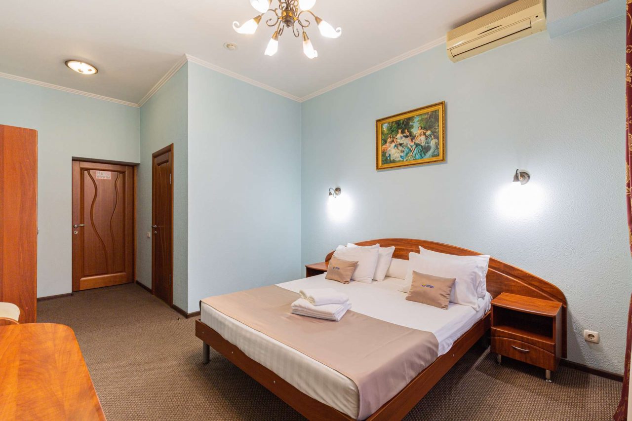 В комнате на стене висит картина в золотой раме.