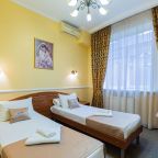 Кровати покрыты бежевыми покрывалами и белыми простыням.