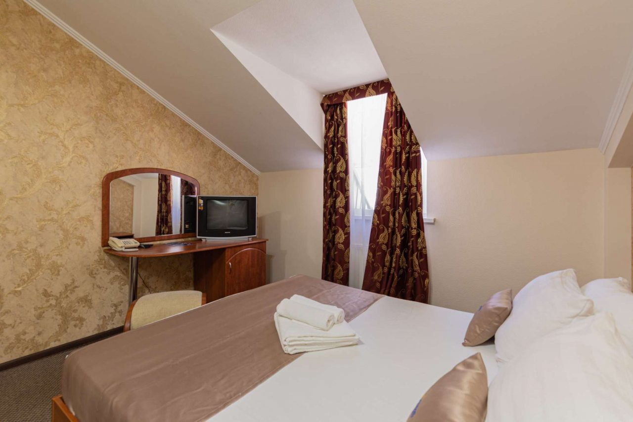 Окно с белыми шторами и золотистыми портьерами.