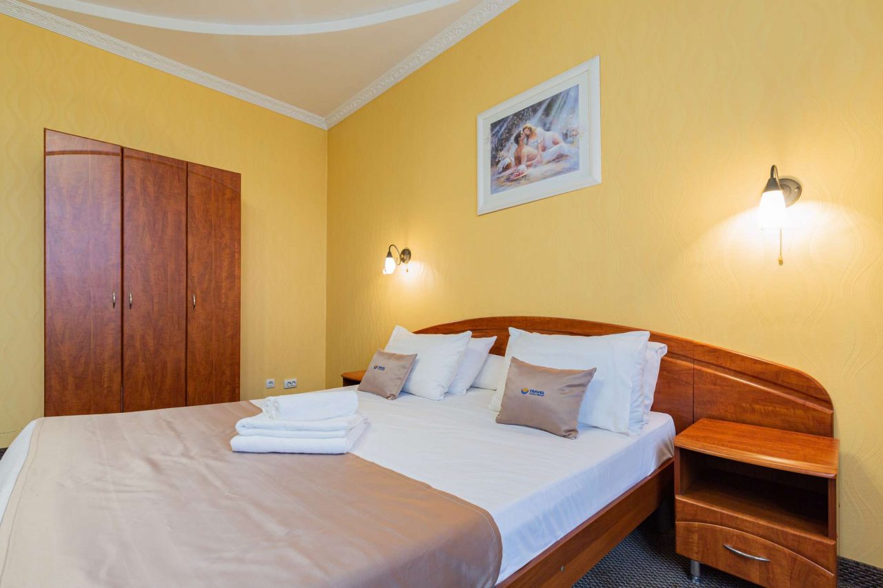 Двуспальная кровать с деревянным изголовьем.