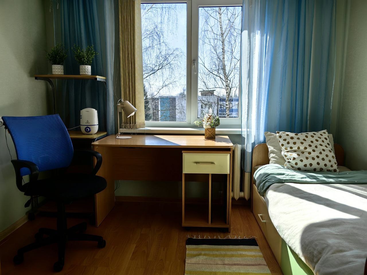 Спальная комната с одноместной кроватью и рабочей зоной.