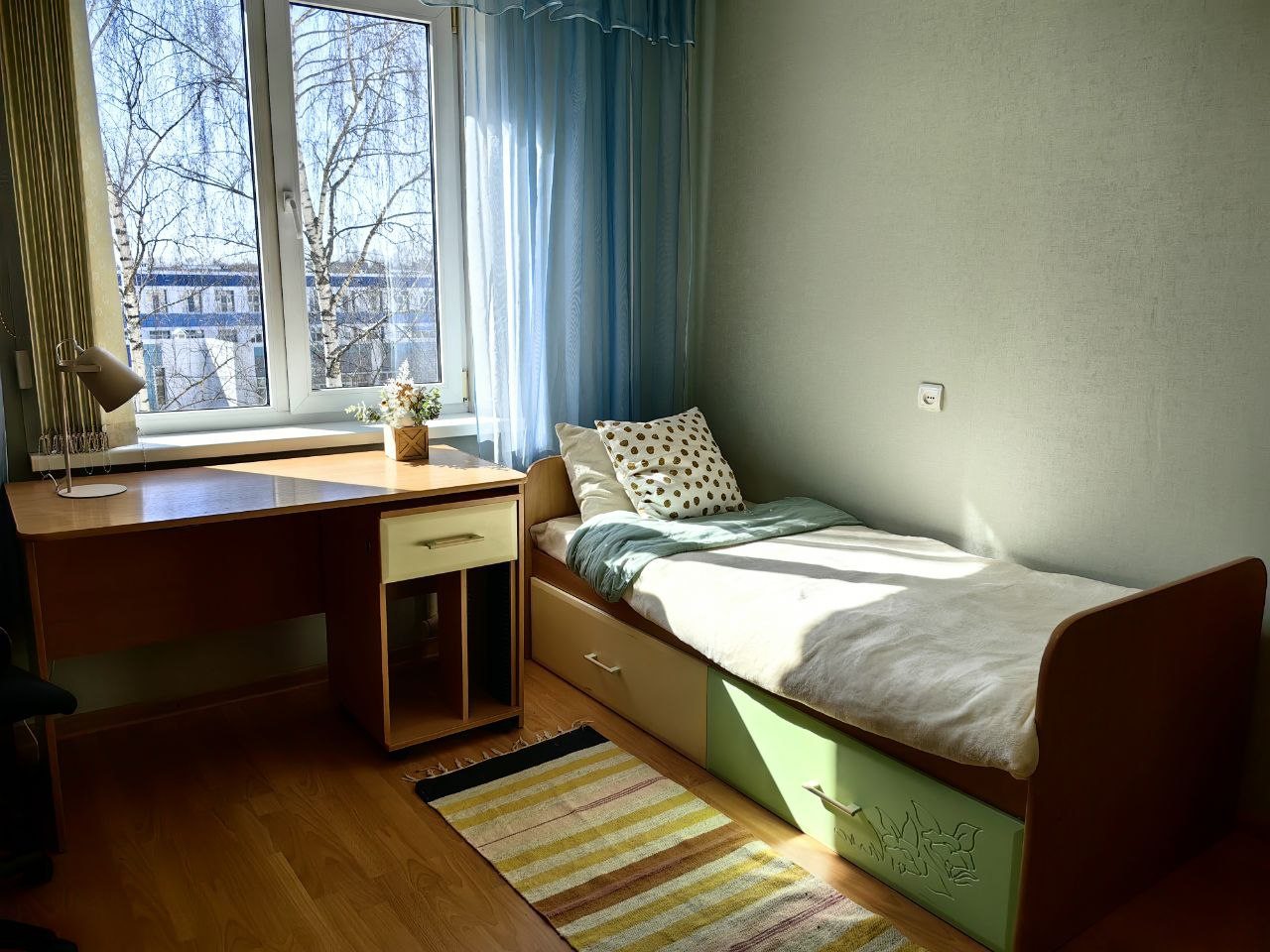 Спальная комната с одноместной кроватью и рабочей зоной.