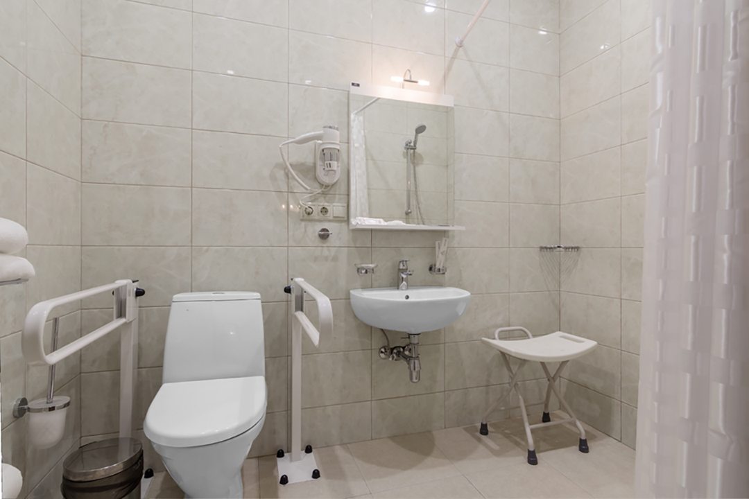 Оборудованная для маломобильных людей ванная, поручни, стул.